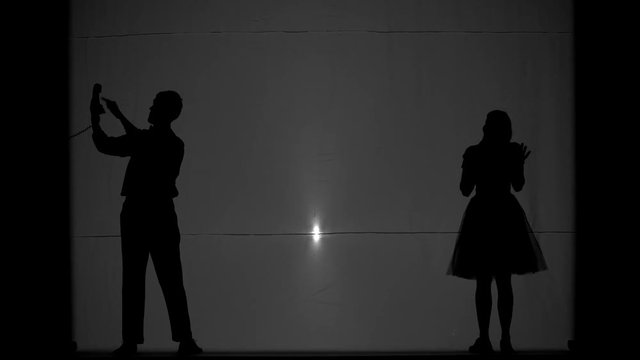 Shooting people and their shadows on a white background. A man phoning his beloved woman, agreeing to meet. Prepare Goodbye.