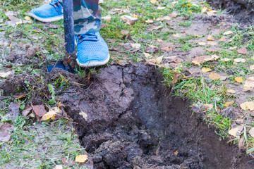 Fototapeta premium Man digging a ditch with a shovel in autumn