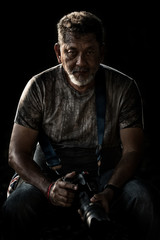 portrait Photographer men look at camera in low key light on a black background.