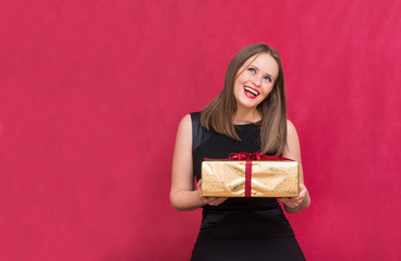 1 white girl with a gift in her hands rejoices laughing on a red background