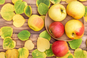 Ripe apples on the table with autumn leaves. Top view.