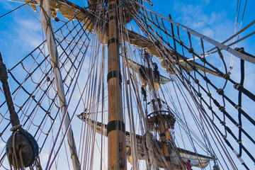 Sailors work with sails at a height on a traditional sailboat