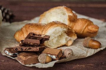Coffee and fresh croissant for breakfast on rustic wooden table. Chocolate croissant with cappuccino