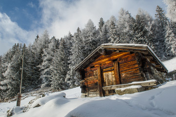 an old wooden cottage in a snow covererd landscape in  the swiss alps