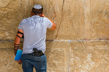 Man with gun praying inside the synagogue at the Western Wall (Wailing Wall) in Jewish Quarter, Old City, Jerusalem, Israel.