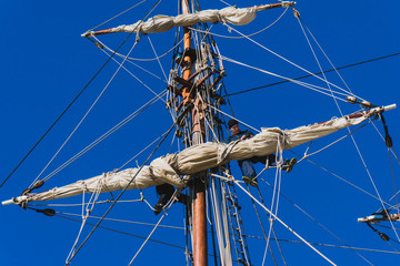 Sailors work with sails at a height on a traditional sailboat