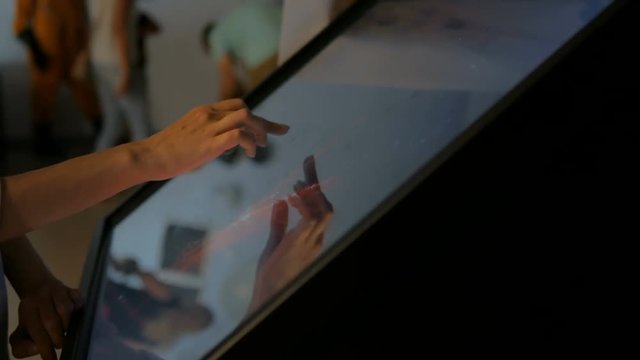 Woman using interactive touchscreen display at modern museum. Education and technology concept