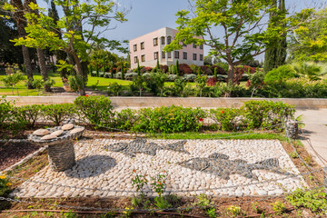 Stone sculpture composition two fish and five loaves of bread in landscape park, Church of Mount of Beatitudes at the Sea of Galilee, Israel.