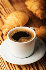 Cup of coffee with croissants on a wooden table