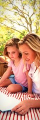 Mother and daughter reading book while father and son playing