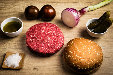 the main ingredients to make a tasty barbecue hamburger: meat, oil, salt, onion, tomatoes, pickles and bread
