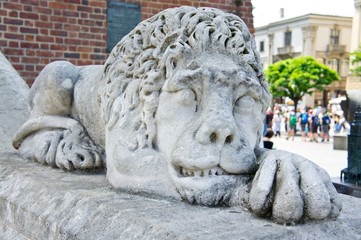 Stone sculpture of a lion lying in front of the entrance to an old building