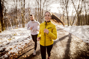 Couple running on the road in nature in winter.