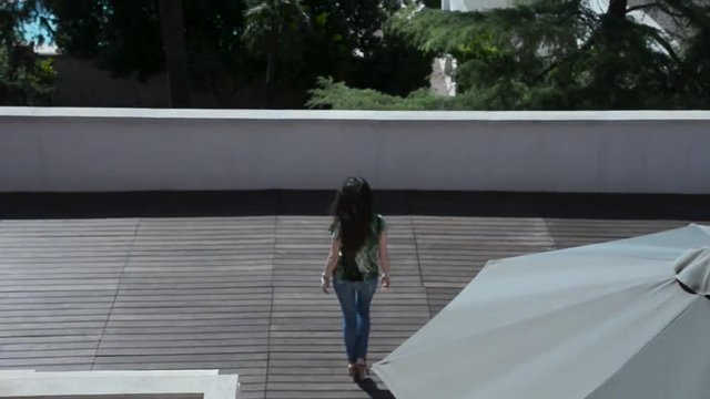 giovane donna cammina sul terrazzo di una villa con giardino