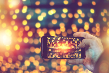 hand holding smart phone to taking photo of lighting decorate in festival.
