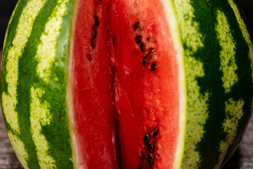 Closeup of juicy ripe red watermelon on a wooden table. One piece cut out.