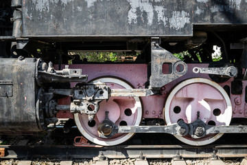 Wheels of the old steam locomotive of red color and the elements of the drive