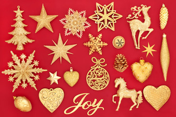 Christmas gold joy sign and bauble decorations on red background. Traditional Christmas greeting card for the holiday season.