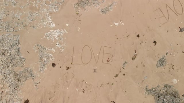 Aerial view of a wild beach with a text love on a sand. Hashtag love. Bali island.