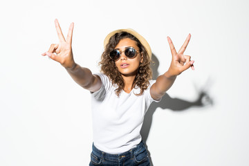 Young curly woman in sunglasses and straw hat with peace gesture isolated on white background