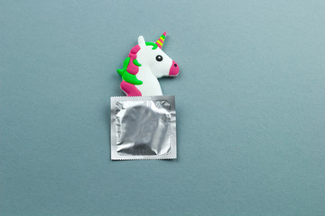 little unicorn toy head and condom  on a blue and green paper background,flat lay,  copy space