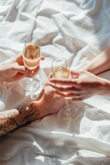 cropped shot of couple with glasses of champagne holding hands on ned