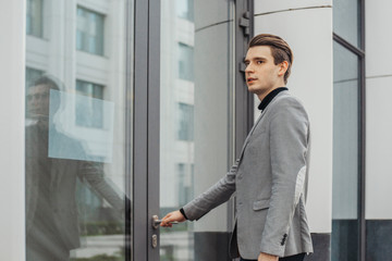 Close up of young business man opening door of modern business center.