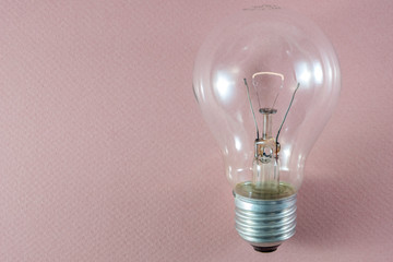 Glowing light bulb on pink background useful to demonstrate concepts e.g. energy, creativity or idea generation