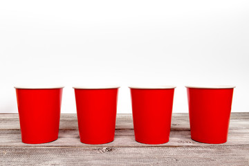 Four red paper disposable cups for coffee and nonalcoholic drinks on wooden background