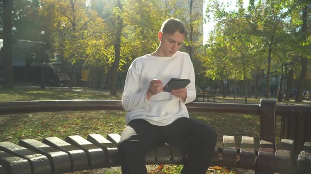Young guy is reading a book in the park