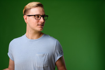 Young handsome man with blond hair against green background