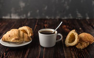 Cup of coffee with croissants on a wooden table