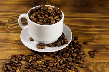 Coffee beans in white cup on wooden table