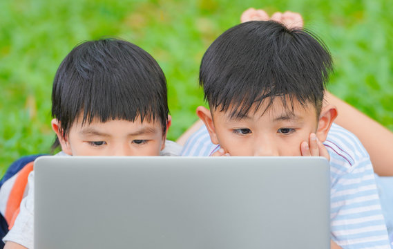 Kids using laptop, Summer school concept, Asian children are playing laptop computer in the park.