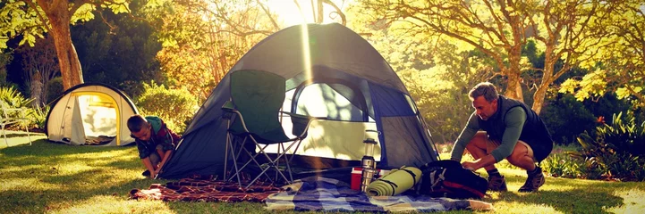 Fototapete Camping Junge baut das Zelt auf dem Campingplatz auf