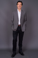 Portrait of mature handsome businessman against gray background