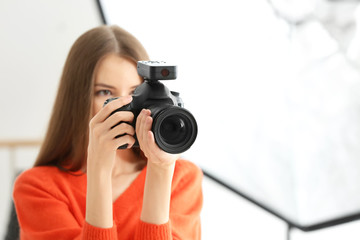 Naklejka premium Young female photographer working in studio