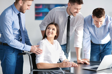 Young woman in wheelchair with colleagues at workplace