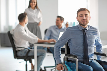 Young man in wheelchair at workplace