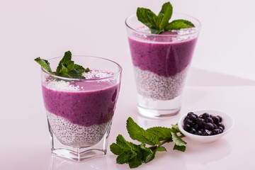 Raspberry white pudding in a glass close-up. Purple dessert with chia seeds and coconut