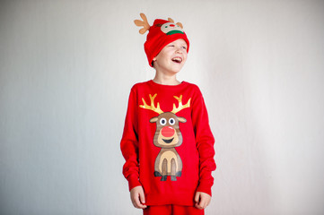 Cute boy dressed in festive costumes of Santa's Deer decorate Christmas tree with balls and garlands. Children play and wait for gifts. Christmas Eve
