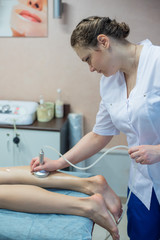 Obraz premium The doctor-cosmetologist performs a vacuum-roll massage of the buttocks and legs of a young woman. Masseuse does her job with the help of the apparatus of correction