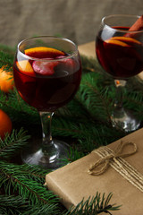 Mulled wine in glasses. Citrus fruits and cinnamon sticks. Christmas decor made of fir branches. Presents.