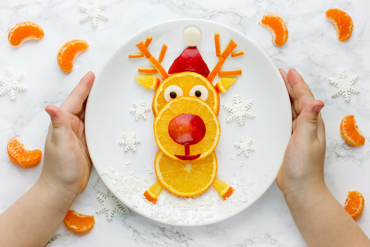 Child Holding Plate With Edible Fruit Reindeer, Christmas Food Art