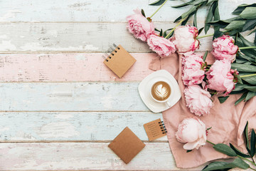 Flat lay cup of coffee and peonies on shabby chic background. © victoria