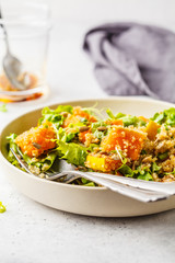 Warm quinoa and pumpkin salad in a white plate.