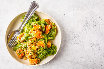 Warm quinoa and pumpkin salad in a white plate, top view, copy space.