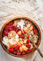 Trendy vegan bowl of oatmeal porridge with berries, raw vegan balls and peanut butter.
