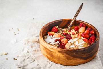 Trendy vegan bowl of oatmeal porridge with berries, raw vegan balls and peanut butter, copy space.