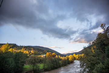 Stormy mountain river with autumn trees in the background.